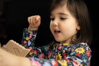 Child playing with wooden blocks against a dark background