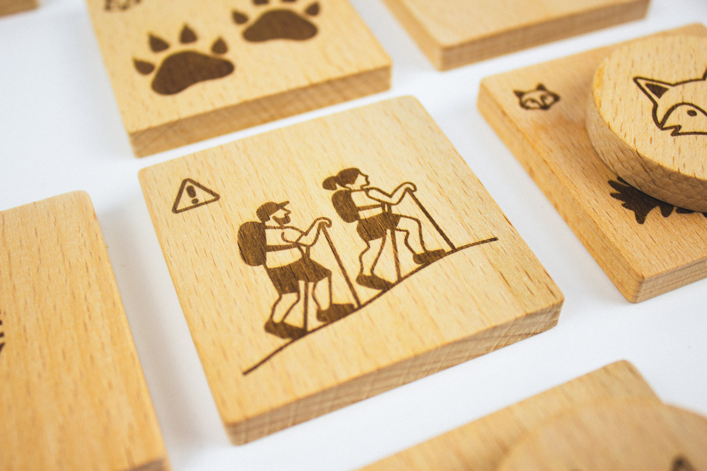 Zoom on engraved wooden tile showing hikers – part of Pure Play’s Forest Animal Rescue board game promoting nature learning and family play.