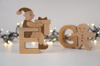Wooden toy figure of a elf opening a gift with Christmas lights in the background