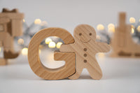 Wooden letter 'G' shaped like a gingerbread man with blurred lights in the background