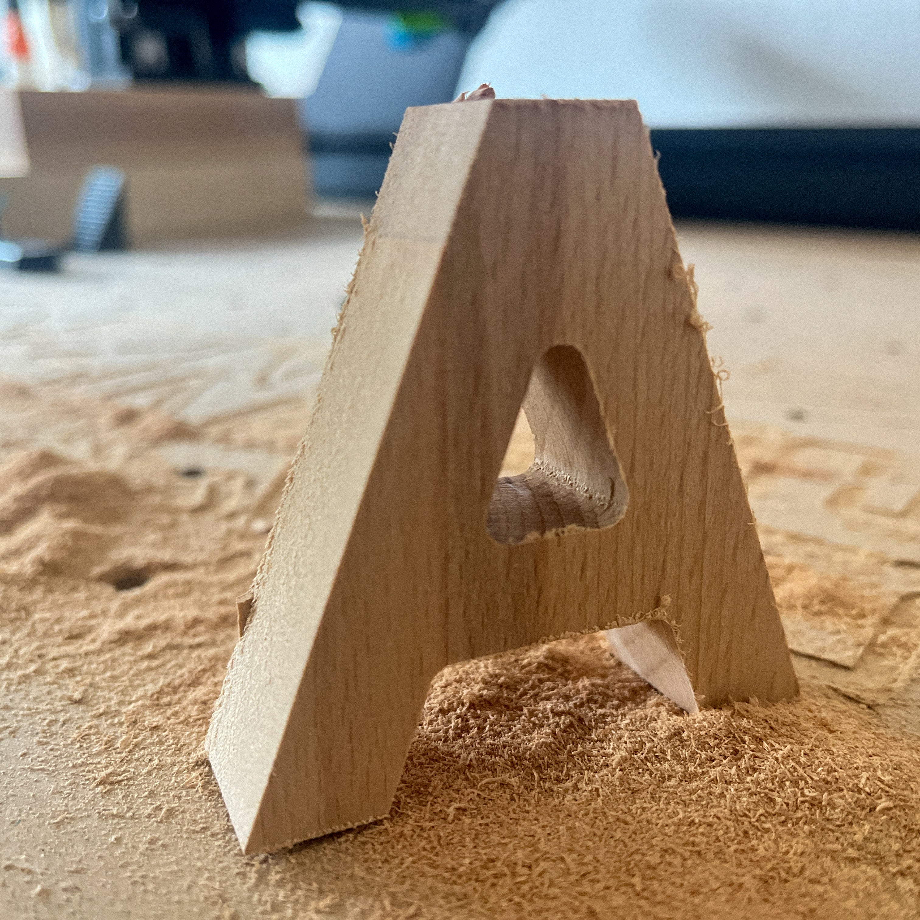 Wooden letter 'A' on a wooden surface with sawdust