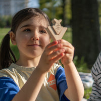 Young girl holding a wooden toy in a park setting