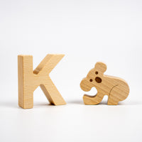 Wooden letter 'K' and wooden koala toy on a white background