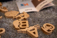 Wooden letters on a textured surface with a book in the background