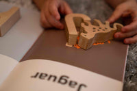 Wooden letter 'J' being used to stamp on a piece of paper with 'Jaguar' printed on it.