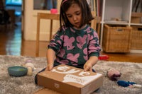 Child playing with a box labeled 'ABC ANIMALS' on a carpeted floor.